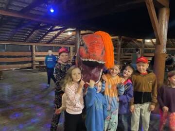 Zabawa z dinozaurem Dzieci bawią się z kostiumem dinozaura pod dachem